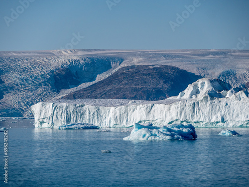 Eisberg in einem gr  nl  ndischen Fjord mit Gletscher im Hintergrund
