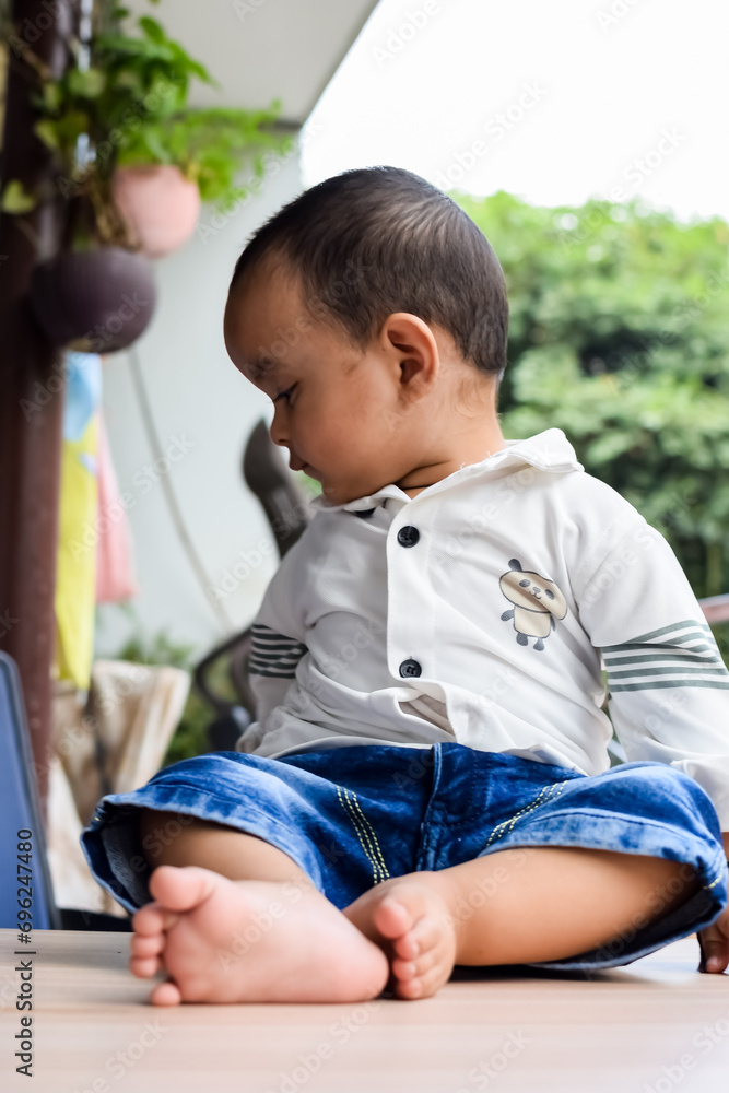 Baby boy at home balcony. Bright portrait of happy child sitting on the table. Little 1 year old boy during the day light at house balcony. Baby boy at home balcony. Bright portrait of happy child sitting on the table. Little 1 year old boy during the day light at house balcony.