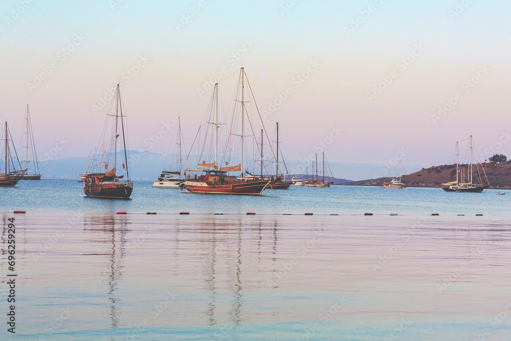 Sailboats at the harbor of Bodrum at first light with pastel tones sky and purple mountains at background. 14 October, 2023. Bodrum, Turkey (Turkiye)
