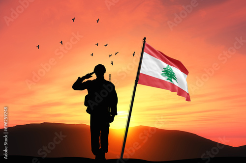 Silhouette of a soldier with the Lebanon flag stands against the background of a sunset or sunrise. Concept of national holidays. Commemoration Day. photo