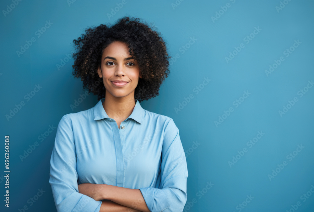 Confident young woman with curly hair posing against a serene blue background, exuding professionalism. Confident young woman with curly hair posing against a serene blue background, exuding professionalism.