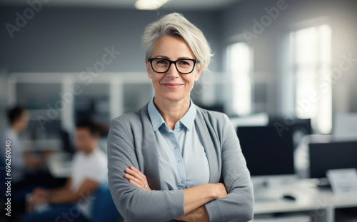 Confident professional woman with silver hair and glasses smiling.
