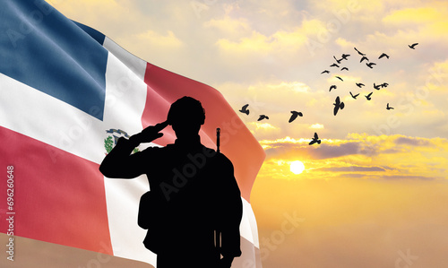 Silhouette of a soldier with the Dominican Republic flag stands against the background of a sunset or sunrise. Concept of national holidays. Commemoration Day. photo