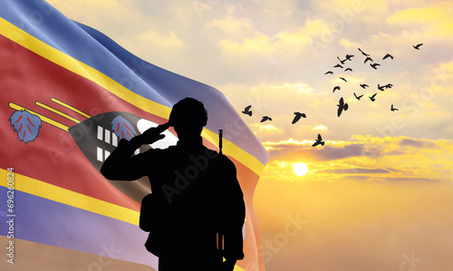 Silhouette of a soldier with the Eswatini flag stands against the background of a sunset or sunrise. Concept of national holidays. Commemoration Day. photo