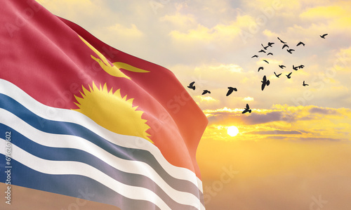 Waving flag of Kiribati against the background of a sunset or sunrise. Kiribati flag for Independence Day. The symbol of the state on wavy fabric. photo