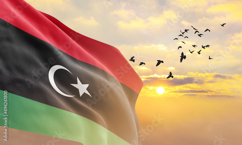 Waving flag of Libya against the background of a sunset or sunrise. Libya flag for Independence Day. The symbol of the state on wavy fabric. photo