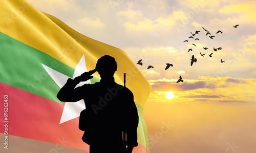 Silhouette of a soldier with the Myanmar flag stands against the background of a sunset or sunrise. Concept of national holidays. Commemoration Day.