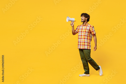 Full body young Indian man he wears shirt casual clothes hold in hand megaphone scream announces discounts sale Hurry up isolated on plain yellow color background studio portrait. Lifestyle concept.