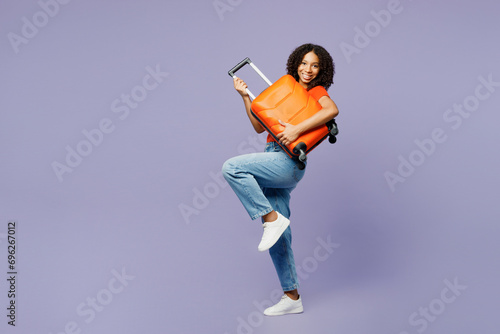 Traveler little kid teen girl wear orange t-shirt hold pov playing guitar isolated on plain purple background. Tourist travel abroad in free spare time rest getaway. Air flight trip journey concept. photo