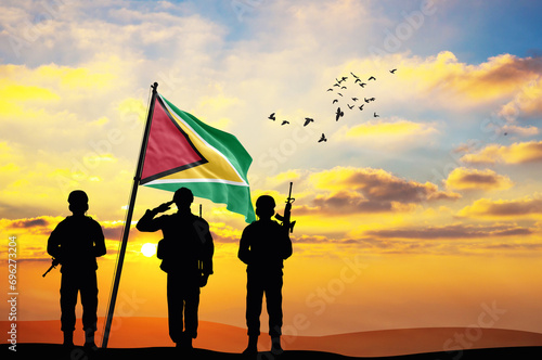 Silhouettes of soldiers with the Guyana flag stand against the background of a sunset or sunrise. Concept of national holidays. Commemoration Day. photo