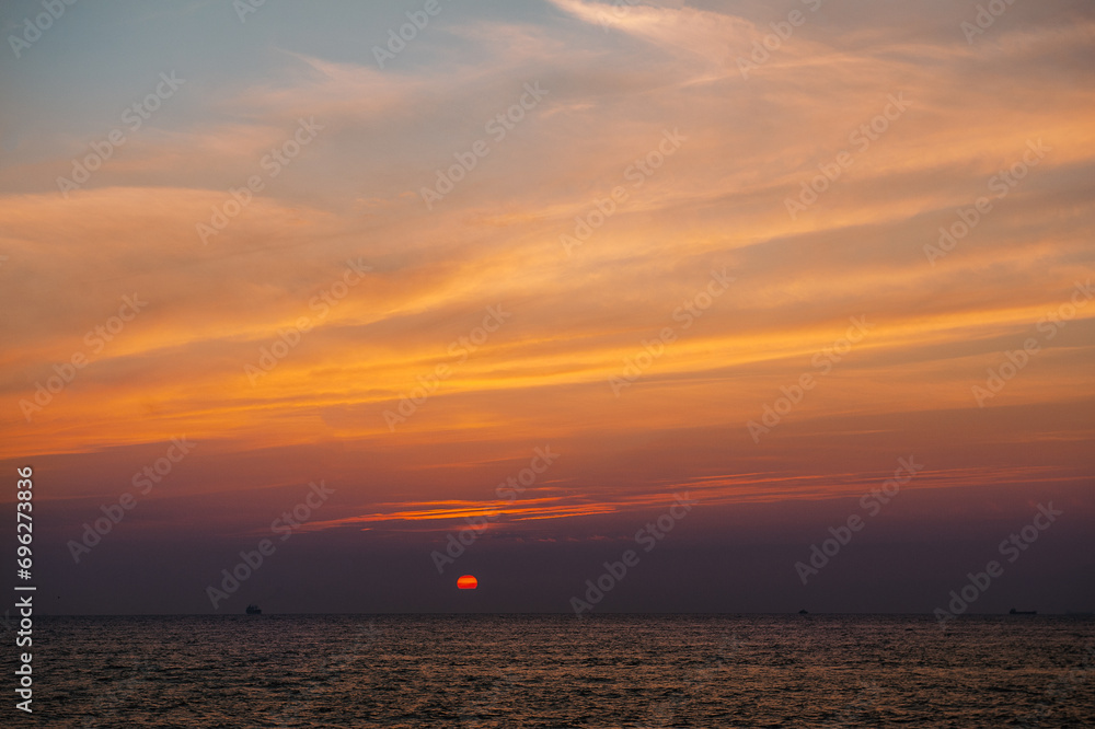 Naklejka premium Beautiful sunset landscape with dramatic sky, sun and sea water