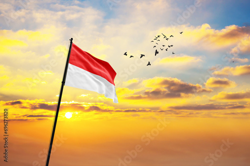 Waving flag of Indonesia against the background of a sunset or sunrise. Indonesia flag for Independence Day. The symbol of the state on wavy fabric.