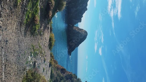 Praia de Almograve beach with ocean waves, cliffs and stones, wet golden sand and green vegetation at wild Rota Vicentina coast, Odemira, Portugal photo