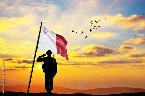 Silhouette of a soldier with the Malta flag stands against the background of a sunset or sunrise. Concept of national holidays. Commemoration Day.