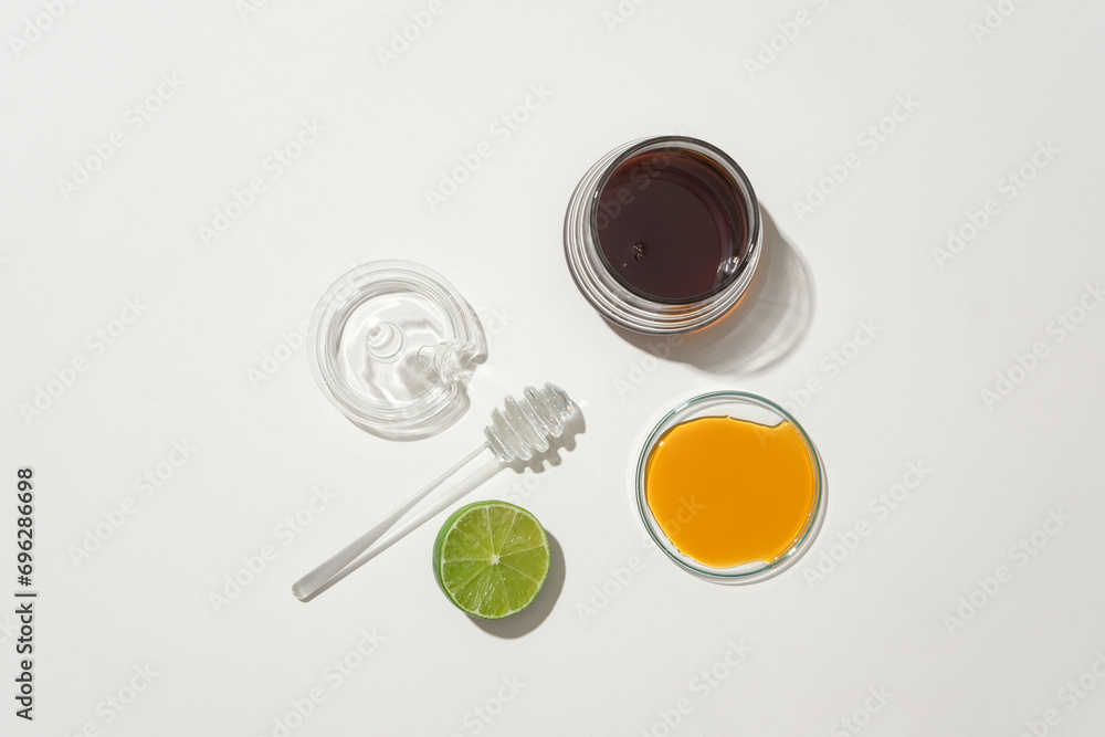 Honey is served in glass containers and half a lemon is displayed on a white background. Natural ingredients to make tea to support health. Top view. Honey is served in glass containers and half a lemon is displayed on a white background. Natural ingredients to make tea to support health. Top view.