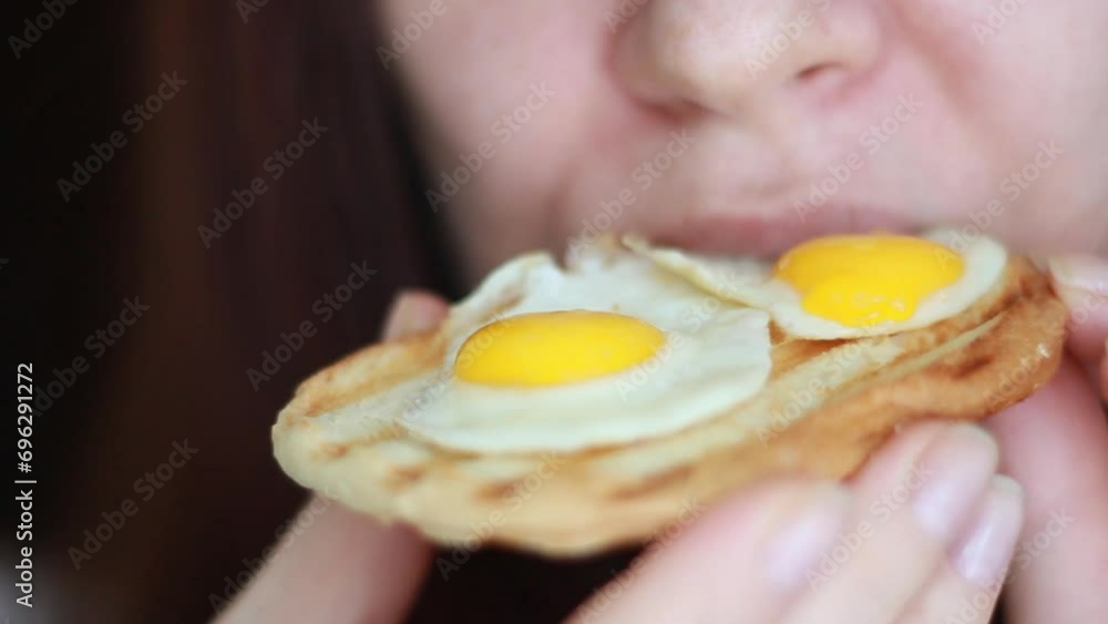 Woman eating toast with quail eggs for breakfast. Close-up of a fried egg sandwich