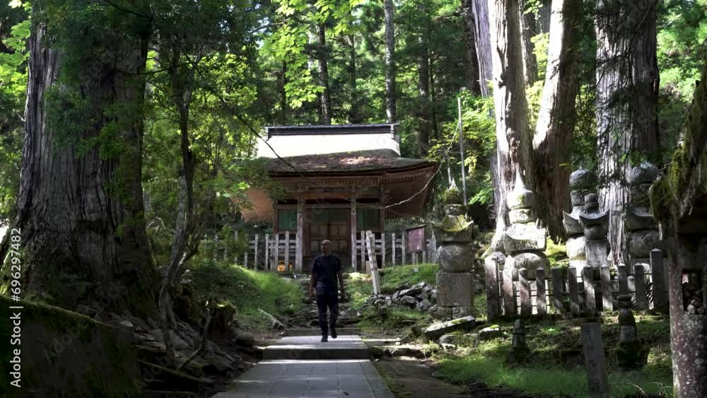 Solo Male Hiker Walking Back Along Path In Koyasan Forest With Temple Lodging In Background. Static Shot Solo Male Hiker Walking Back Along Path In Koyasan Forest With Temple Lodging In Background. Static Shot