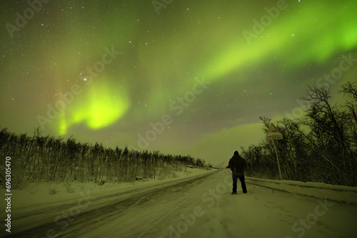 Fototapeta Naklejka Na Ścianę i Meble -  Silhouette of a person looking at aurora borealis dance in the arctic night