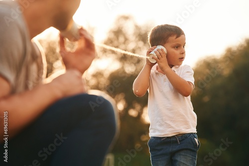 With string can phone. Father and little son are playing and having fun outdoors photo