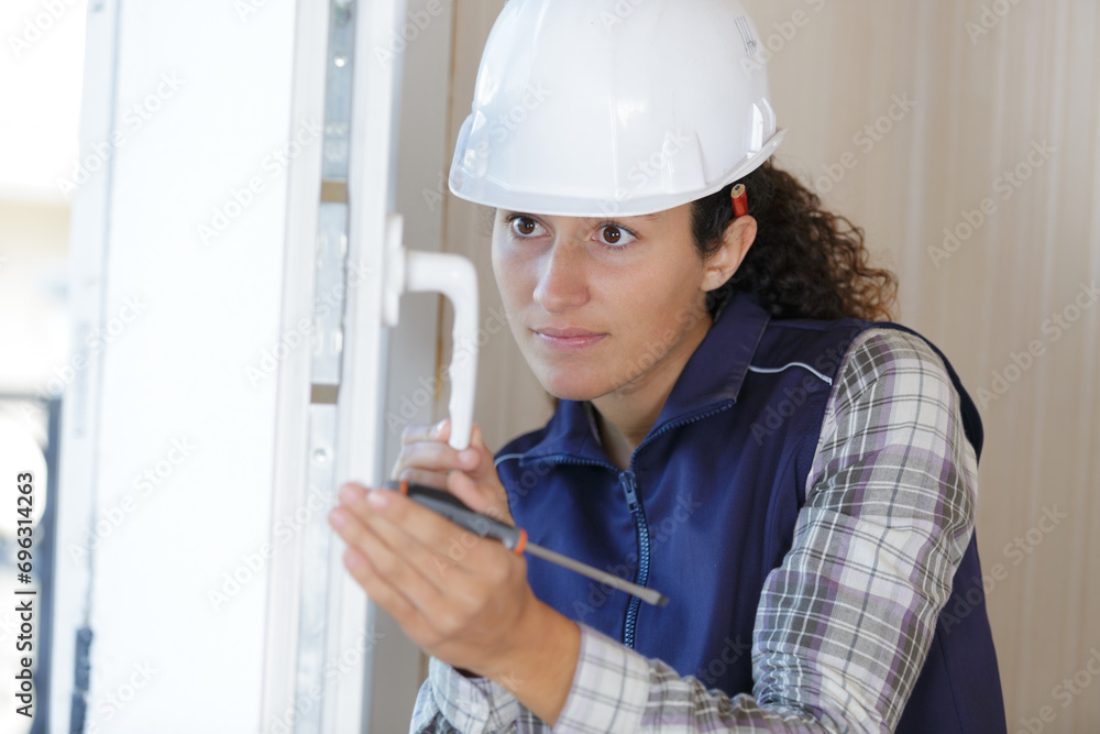woman builder working using a screwdriver and fix the door woman builder working using a screwdriver and fix the door
