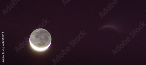 Waning crescent moon against a purple and black night sky. photo