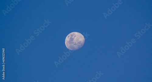 Fényképezés Waning gibbous moon in daylight against a blue sky.