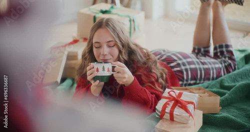 Beautiful woman drinking coffee while lying on floor during Christmas photo