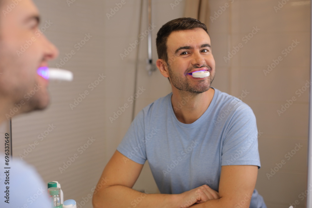Fototapeta premium Man whitening his teeth at home 