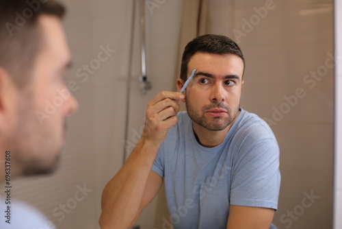 Man using special shaving tool for the surroundings of the hairy eyebrows 