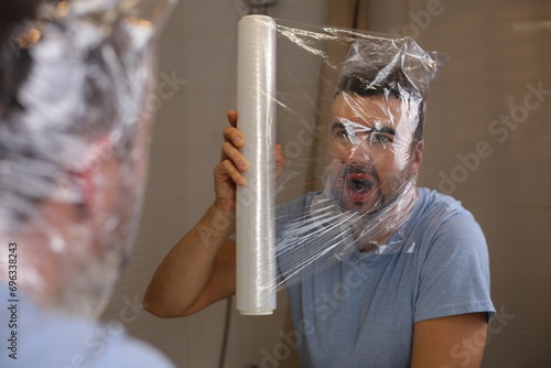 Man covering his face with plastic paper 