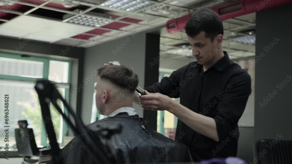 A male brunette hairdresser cuts a haircut for a handsome young man in a barbershop, general plan. Modern and fashionable haircut. Professional barbershop. Slow motion A male brunette hairdresser cuts a haircut for a handsome young man in a barbershop, general plan. Modern and fashionable haircut. Professional barbershop. Slow motion