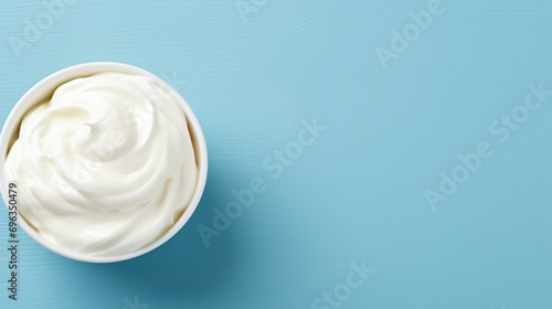 Bowl of white cream on blue background with copy space photo