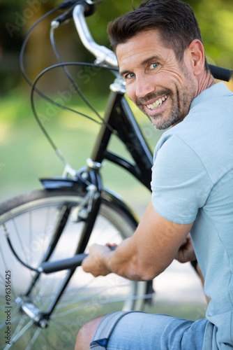 happy middle-age man using air pump for his bike