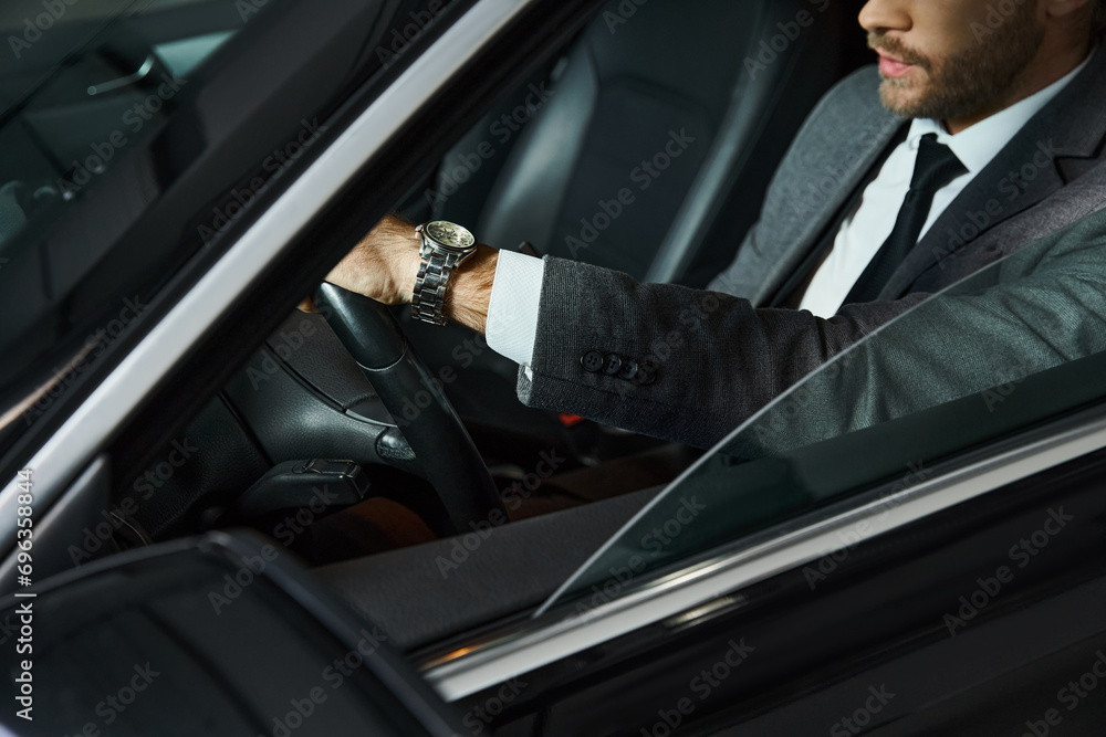cropped view of elegant man with tie and wristwatch behind steering wheel, business concept