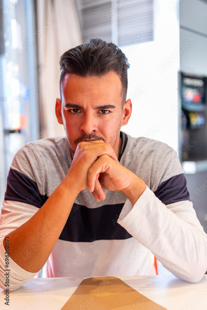 Serious young Latino man awaits order. Serious young Latino man awaits order.