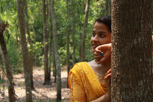 Young Indian girl hiding behind the tree. Portrait of young Indian girl behind the tree in park. Full face of girl behind tree. © #CHANNELM2