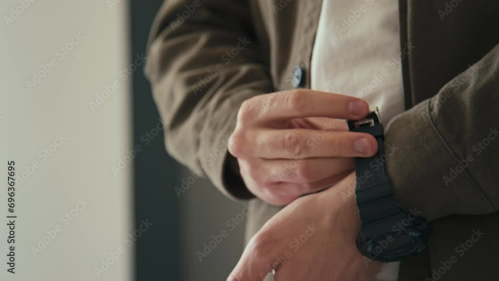 Side closeup of male hands putting on electronic wristwatch before leaving home Side closeup of male hands putting on electronic wristwatch before leaving home