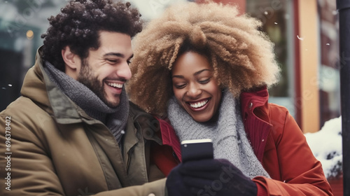 copy space  stockphoto  Multiracial couple having fun  laughing using phone outdoors on winter day. Internet technology  communication. Smartphone  cellphone for chatting or surfing.