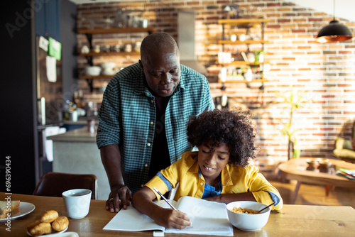 Father helping his son with homework at home photo