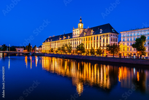 Evening cityscape of the University of Wrocław building illuminated and reflected in the Odra river in Wrocław, Poland