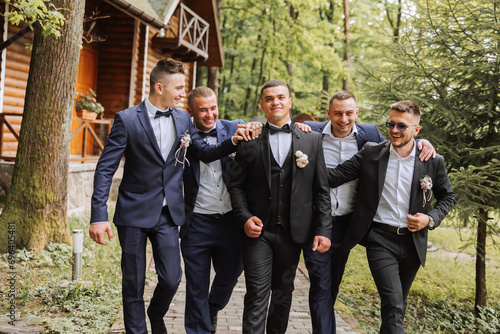 Cheerful, young, energetic witnesses of the groom next to the groom. Friends congratulate the groom. Groom and his funny friends having fun on the wedding day of the newlyweds. photo