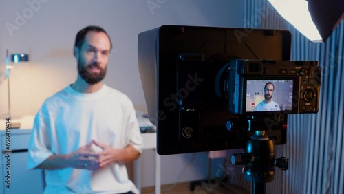 A young male blogger records a video with teleprompter for his YouTube channel in his studio. photo