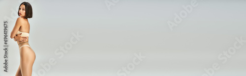 banner of young asian woman in seamless pantyhose and beige underwear posing on grey background