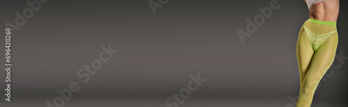 cropped photo of woman in green nylon tights posing on dark grey background, crossed legs banner