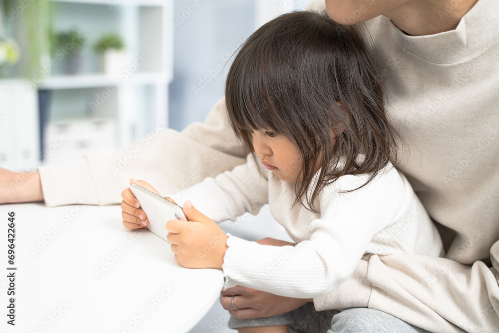 保護者と一緒にスマートフォンを見る幼児 保護者と一緒にスマートフォンを見る幼児
