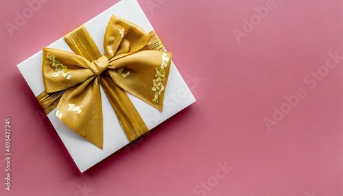 blank gift card with golden bow on pink background top view space for text