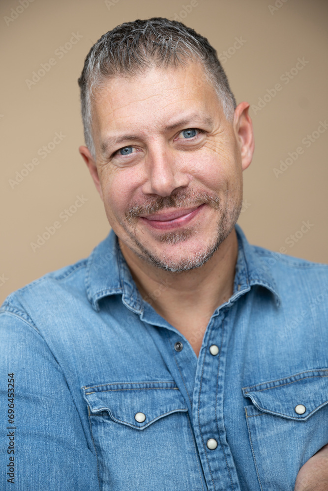 cool man, 46 age, with grey hair, blue jeans, blue shirt, posing in front of brown studio, portrait, concept, business, casual cool man, 46 age, with grey hair, blue jeans, blue shirt, posing in front of brown studio, portrait, concept, business, casual