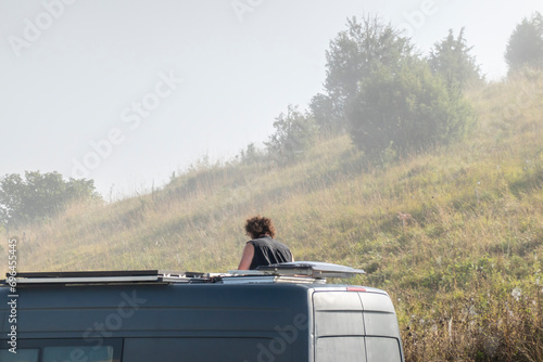 A traveler looks out of the roof window of a caravan park during