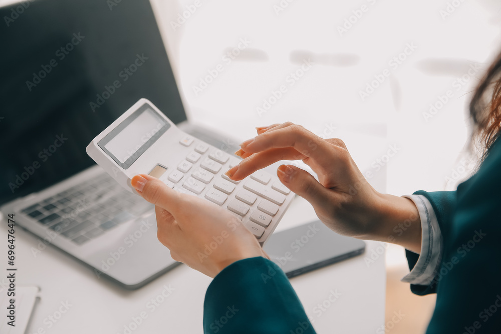 Businessman using a calculator to calculate numbers on a company's financial documents, he is analyzing historical financial data to plan how to grow the company. Financial concept. - obrazy, fototapety, plakaty 