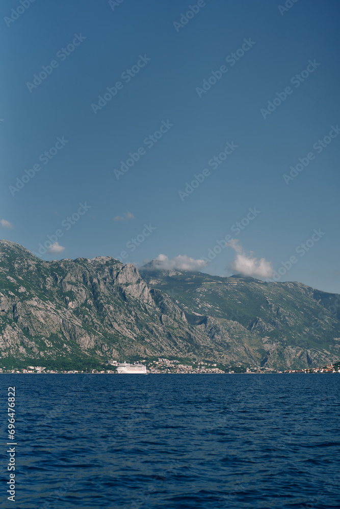 Cruise ship sails along the sea along the high mountain coast